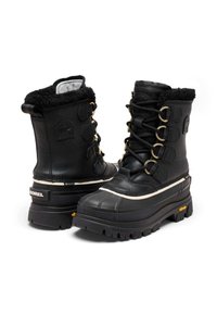 Bottes d'hiver imperméables noires avec un col doublé de fourrure, des œillets en métal et une semelle en caoutchouc épaisse avec un motif de bande de roulement texturé.