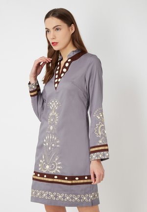 Vestido gris con escote en V, acentos marrones y bordados intrincados en blanco y beige. Mangas largas con puños detallados y patrones elegantes.