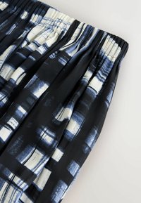 Gonna a righe bianche e nere con vita elastica arricciata, caratterizzata da forme astratte in tonalità di blu e un tessuto leggero e liscio.