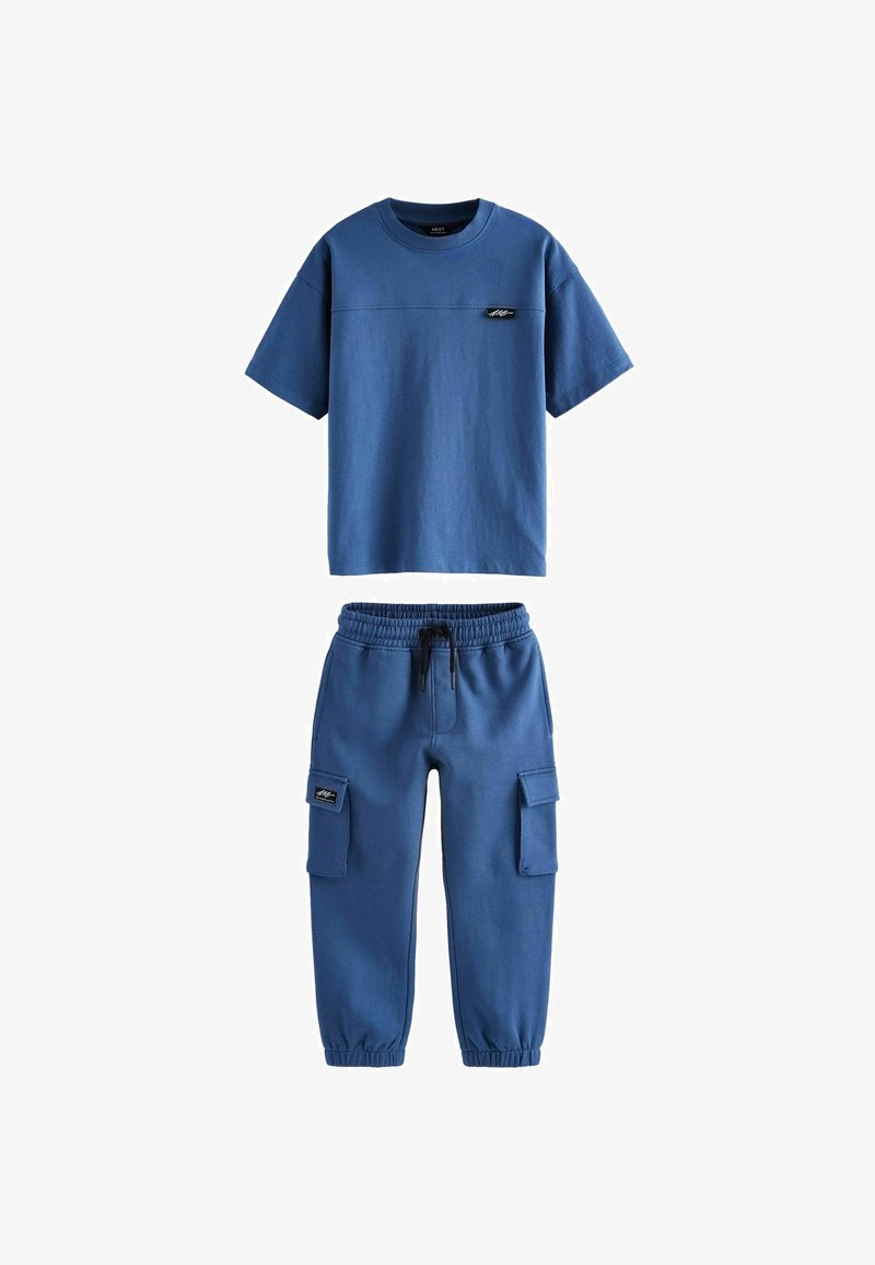 Blå bomulds t-shirt med korte ærmer, der har en horisontal søm og logo-patch, parret med matchende cargo-stil bukser med elastisk talje.