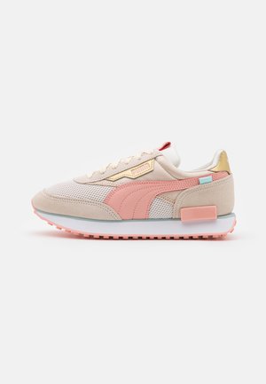 Beżowo-różowe sneakersy Puma z panelami z siateczki i zamszu, różową gumową podeszwą, złotym akcentem na pięcie i logo Puma po boku i na języku.