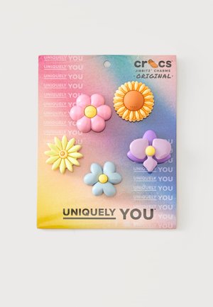 Cinq breloques Crocs Jibbitz en forme de fleur colorée sur une carte dégradée arc-en-ciel avec le texte "Uniquely You".