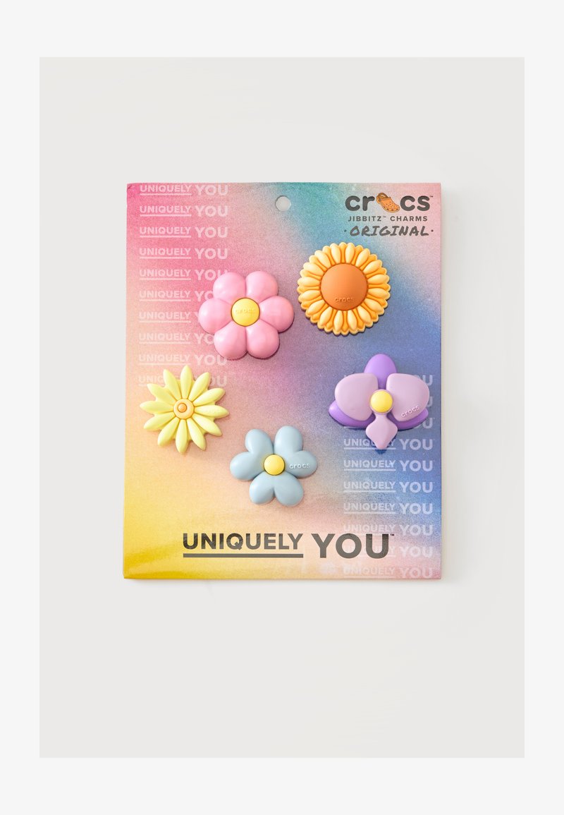 Cinq breloques Crocs Jibbitz en forme de fleur colorée sur une carte dégradée arc-en-ciel avec le texte "Uniquely You".