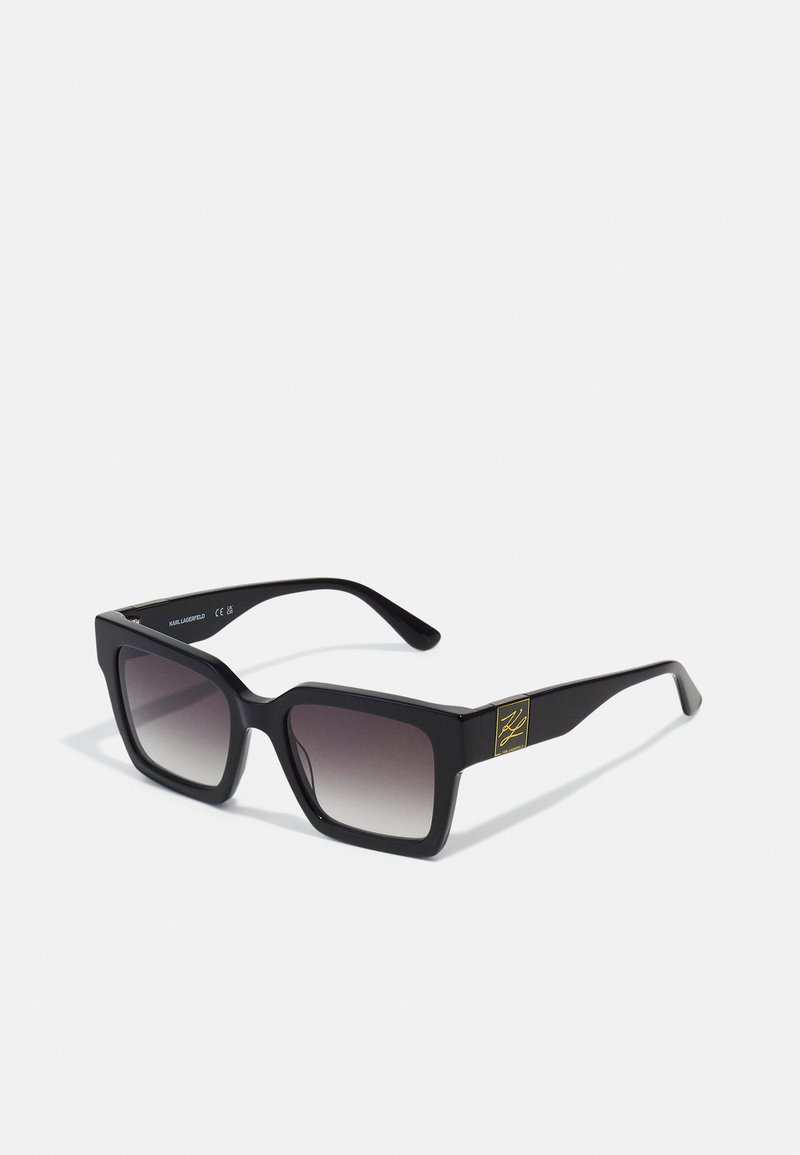 Black acetate sunglasses with a bold rectangular shape, gradient lenses, and gold logo accent on the temple. Matte finish.