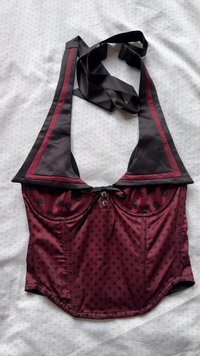 Bordeaux pöttyös crop top fekete díszítéssel és állítható pántokkal. Mély nyakkivágással, elülső gombokkal és sima szövet textúrával rendelkezik.