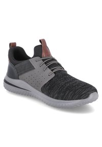 Zapatilla deportiva en negro y gris con upper de punto texturizado, panel de acento gris con perforaciones y una suela de goma suave. Detalle en cuero marrón en el talón.