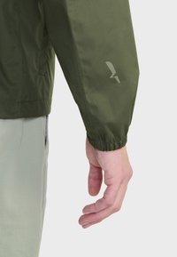 Groene lichtgewicht jas met elastische manchetten, met een subtiele logo-ontwerp op de mouw. Glad oppervlak en een relaxte pasvorm zichtbaar.