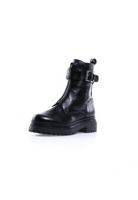 Bottine en cuir noir avec semelle à crampons épaisse, fermeture éclair à l'avant et sangle réglable avec boucle autour de la partie supérieure de la botte.