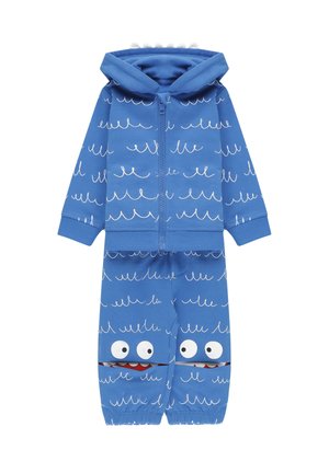 Felpa blu con zip e pantaloni abbinati realizzati in tessuto morbido, caratterizzati da motivi a onda e occhi di cartone con accentuazioni rosse sulle gambe inferiori.