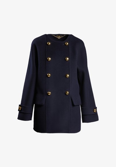 Sötétkék gyapjú kabát egyenes fazonnal, nagy, kerek arany gombokkal és két elülső zsebbel. Széles mandzsettákkal rendelkezik, melyeken gomb díszítések találhatók.
