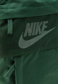 Το πράσινο σακίδιο πλάτης της Nike διαθέτει εξωτερικό από ύφασμα με πλέγμα και το λογότυπο της Nike σε λευκό. Περιλαμβάνει ρυθμιζόμενους ιμάντες και λεπτομέρειες με φερμουάρ.