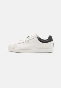Sneaker bianca in pelle con accentuazione nera sul tallone, punta rotonda e suola piatta in gomma. Presenta dettagli del logo e chiusura con lacci standard.