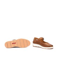 Chaussure en cuir marron avec un design perforé, soutien au talon et bande Velcro. Semelle en caoutchouc blanc avec des motifs de traction et des détails sur la coque des orteils.