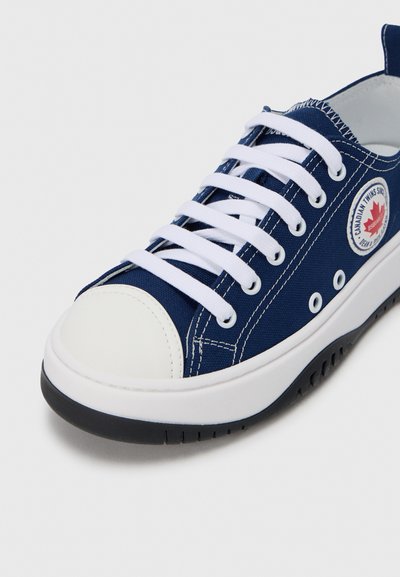 Μπλε ναυτικό πάνινο παπούτσι με λευκά κορδόνια, στρογγυλή μύτη και καουτσούκ κάλυμμα. Διαθέτει λογότυπο και αντίθετες ραφές. Λευκή σόλα με μαύρες λεπτομέρειες.