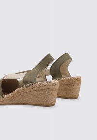 Sandalias de cuña de ante verde con suela de yute trenzada y diseño abierto. Cuenta con laterales elásticos para mayor comodidad y un panel de tela texturizada.