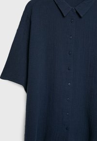 Camicia azzurra navy a bottoni, realizzata in tessuto testurizzato con un design rilassato, dotata di colletto e maniche corte. Sei bottoni coordinati sono visibili.