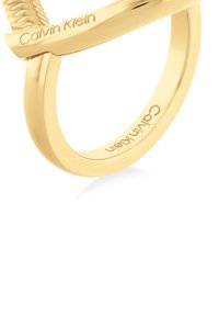 Anello Calvin Klein color oro con banda liscia, dotato di un accento testurizzato e del nome del marchio inciso sulla superficie.