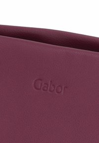 Portefeuille en cuir bordeaux au fini texturé, avec le nom de la marque "Gabor" embossé dans un design subtil.