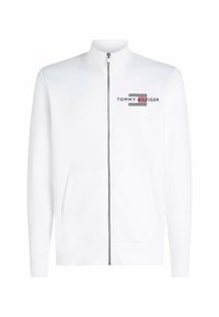 Sudadera blanca con cremallera y cuello alto, presenta un logo "TOMMY HILFIGER" en negro y rojo, dos bolsillos frontales y puños acanalados.