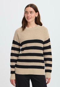 Maglione a strisce beige e nere con texture a costine, scollo rotondo e maniche lunghe. Presenta una vestibilità leggermente ampia e strisce a contrasto.
