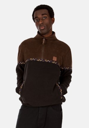 Pullover in fleece marrone con colletto alto, decorato da una fascia a motivo geometrico sul petto e tasche laterali, vestibilità comoda.