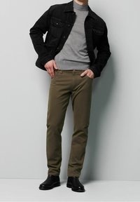 Czarna kurtka dżinsowa, szary sweter z golfem, oliwkowe spodnie i czarne skórzane buty chelsea. Prosty, dopasowany krój, gładkie tkaniny.