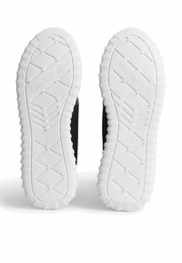 Svart sneaker sula med vit gummiyttersula, med ett texturerat greppmönster och präglad "Calvin Klein Jeans" logotyp.