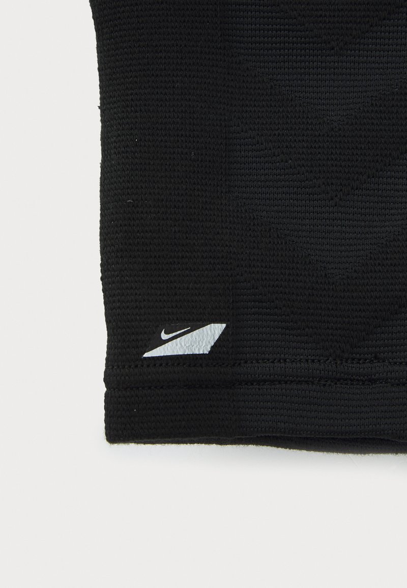 Zwart sportief materiaal met een gestructureerd patroon, met een klein wit Nike swoosh-logo in de rechterbenedenhoek.