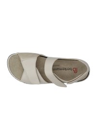 Light beige sandal with cross-over leather straps, open toe, and cushioned insole. Features Velcro closures and a textured sole for grip.