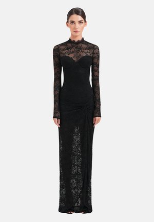 Abito da sera in pizzo nero con maniche lunghe, collo alto, corpetto aderente e dettaglio drappeggiato laterale. Tessuto trasparente con motivo floreale.