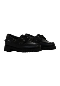 Scarpe in pelle nera con un design arrotondato, lacci frontali e occhielli decorativi. Suola in gomma testurizzata con un motivo di battistrada spesso.