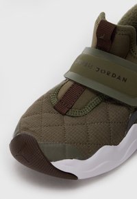 Sněrovací boty olivové barvy s prošívanou textilií, hnědým páskem s textem "Jordan" a strukturovanou hnědou gumovou podrážkou.