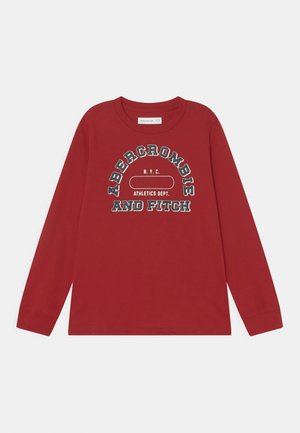 Rød langærmet skjorte med "Abercrombie and Fitch N.Y.C. Athletics Dept." trykt i store hvide og sorte bogstaver på forsiden.