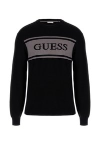 Fekete kötött pulóver szürke vízszintes csíkkal, amelyen vastag fekete betűkkel a "GUESS" felirat található a mellrészen. Kerek nyakkivágás, hosszú ujjú.
