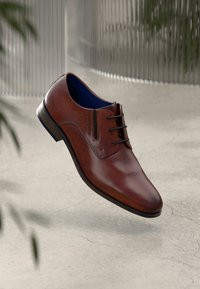 Scarpa elegante in pelle marrone con punta arrotondata, design con lacci, fodera interna blu e suola in legno. La superficie è liscia con una leggera lucentezza.