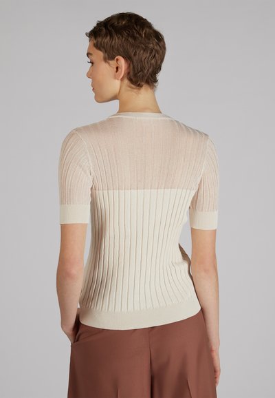 Jasno beżowy sweter z prążkowanej tkaniny, z krótkimi rękawami, z przezroczystą górną częścią i jednolitą dolną częścią, o miękkiej fakturze i dopasowanym kroju.