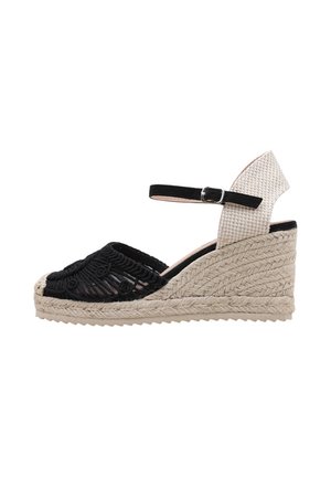 Keilsandale mit schwarzer Häkelsehne, beige geflochtenem Absatz und schwarzem Knöchelriemen mit silberner Schnalle.