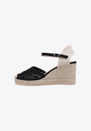Sandalia alpargata con cuña, puntera de crochet negro, talón tejido beige y pulsera negra en el tobillo con hebilla plateada.