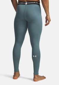 Kapeetava Under Armour retuusit muted teal värviga, millel on tekstuurpind ja must vöökoht valgete logo detailidega.