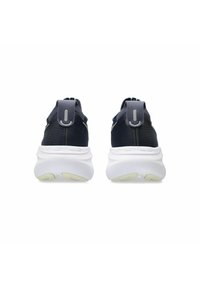 Baskets de sport noires avec une tige en tissu texturé, semelle blanche épaisse et languettes à l'arrière pour faciliter l'enfilage. Détail logo subtil sur le talon.