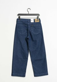 Tummansiniset farkut, joissa on leveä lahje. Takavyötäröllä on "Lee" -merkki ja kaksi takataskua ommeltuine yksityiskohtineen.