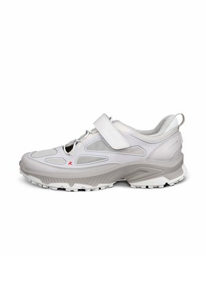 Chaussure de sport gris clair avec panneaux en maille, bride Velcro, semelle épaisse à crampons et languette au talon, vue de côté.