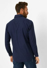 Marineblaues langärmliges Hemd mit glatter Textur, Knopfmanschette und klassischem Kragen. Gerades Rückendesign mit dezenten Musterdetails.