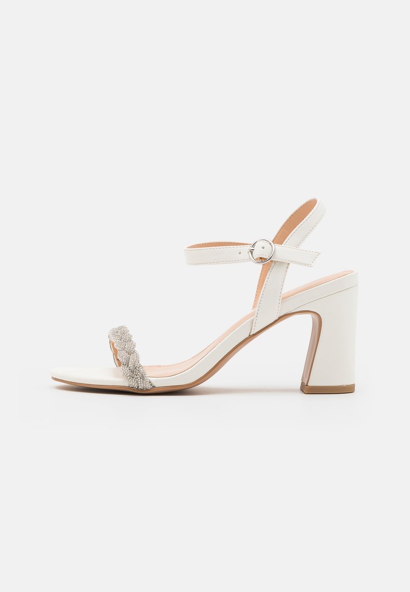 Sandale blanche à talons hauts avec une finition en cuir lisse, une sangle décorative texturée et un talon bloc imposant pour le soutien.