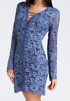 Blaues Spitzen-Minikleid mit langen Ärmeln, floralem Muster und vorderer Schnürung am Ausschnitt, getragen von einer stehenden Person.