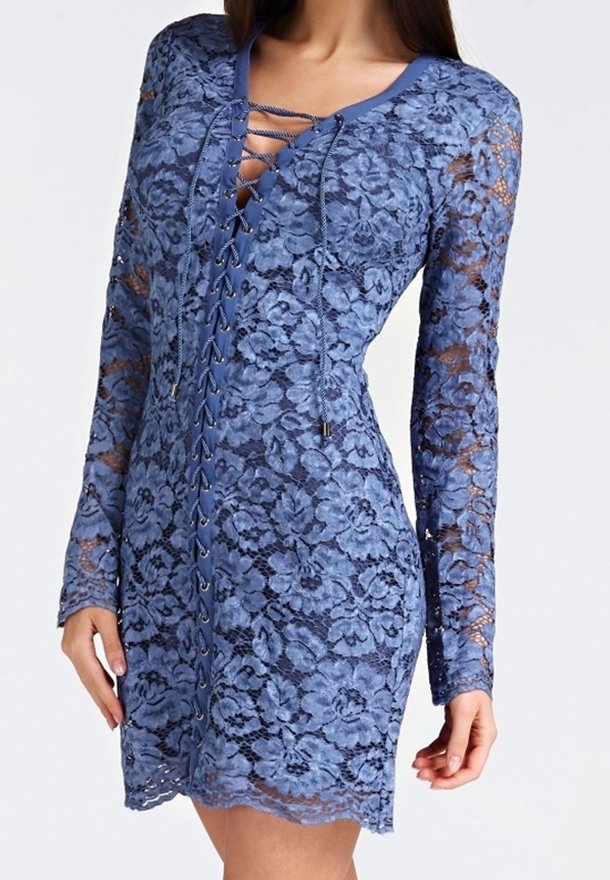 Mini-robe bleue en dentelle avec manches longues, motif floral et encolure à lacets sur le devant, portée par une personne debout.