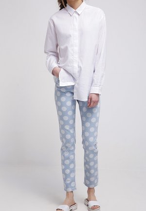 Witte blouse met lange mouwen, lichtblauwe jeans met stippen, en witte instap sandalen. Casual outfit met een relaxte pasvorm en een klassiek ontwerp.