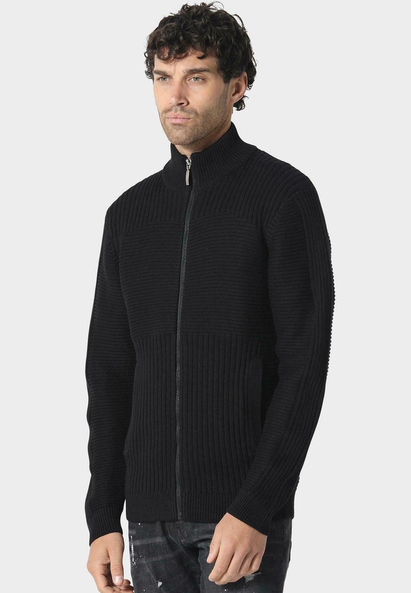 Černá zipová mikina s ribbovanou strukturou, vysokým límcem a bočními kapsami. Má kontrastní hladký panel na hrudi.