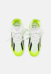 Zapatillas deportivas blancas con acentos en amarillo neón, rayas negras y una parte superior de malla. Presentan una suela texturizada y cordones planos blancos.