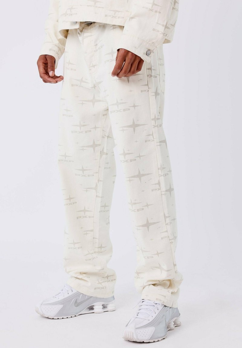 Pantalones blancos con un diseño geométrico en gris claro, de corte recto y con bolsillos laterales, combinados con zapatillas deportivas grises.
